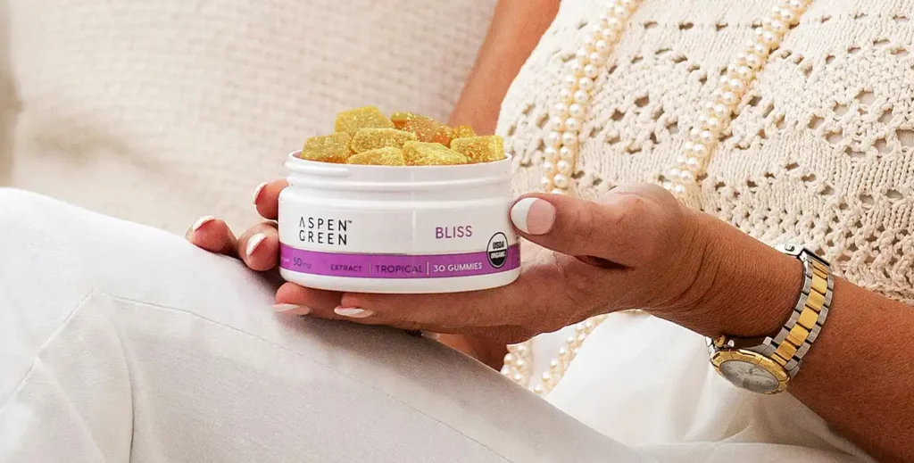 Woman sitting on couch holding Aspen Green Bliss Gummies
